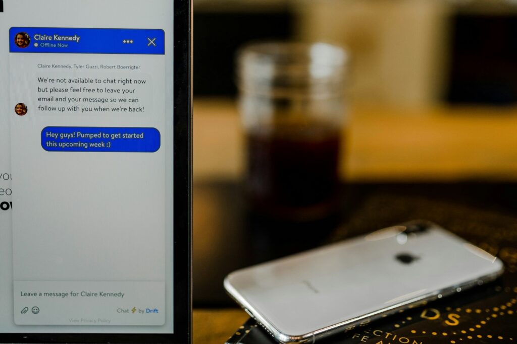 Smartphone met een chatapp open naast een notitieboek op een bureau