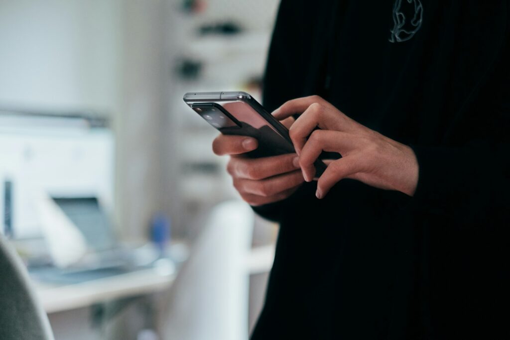 Hand met een smartphone waarop een sms met een link te zien is