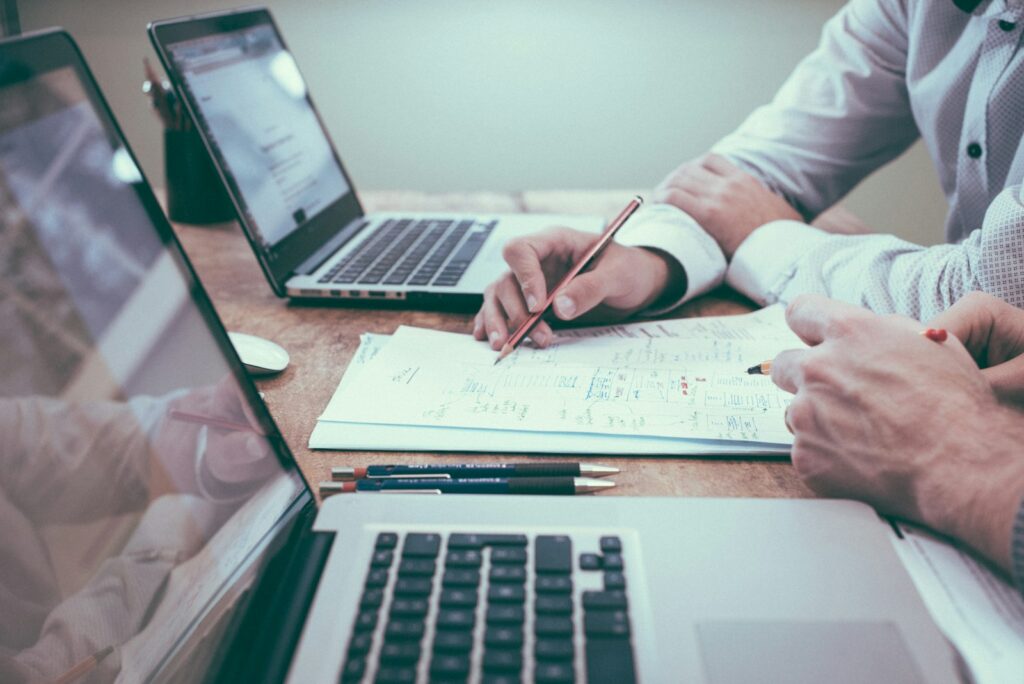 Overleg rond een tafel met een laptop en notitieblok, klaar om te notuleren