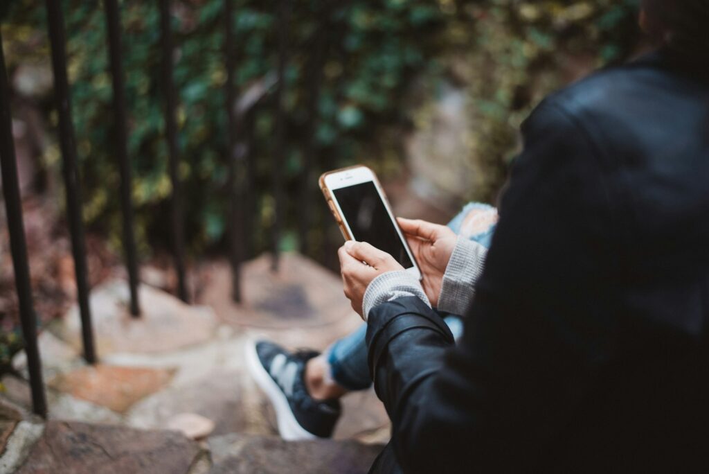 Smartphone met een foto op het scherm naast een laptop op een bureau