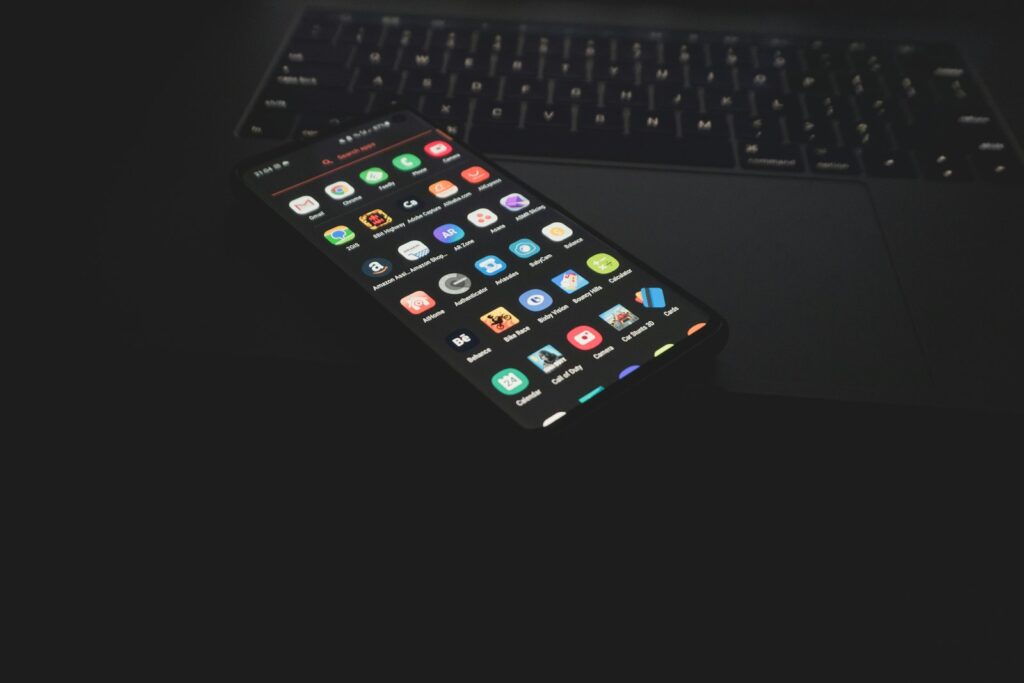 Smartphone met apps op het scherm naast een laptop