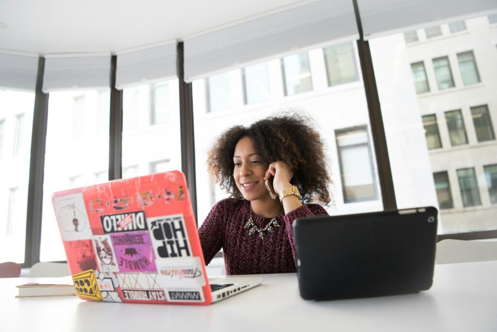 Vrouw aan de telefoon met een laptop voor zich
