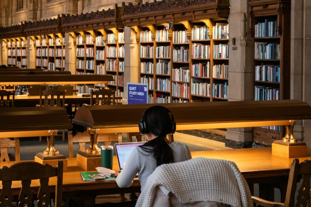 Student achter een laptop in een universiteitsbibliotheek