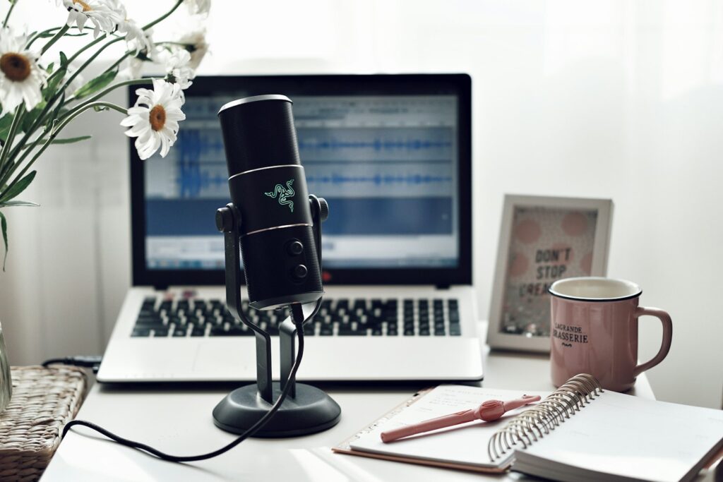 Koptelefoon en laptop op een bureau bij daglicht, klaar om een podcast te luisteren