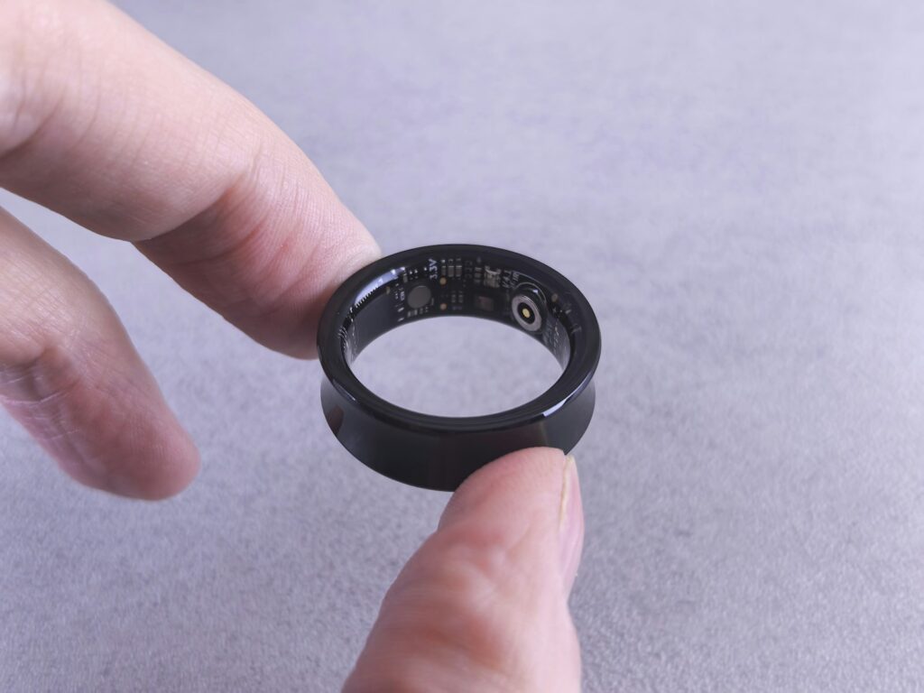 Hand met een slimme ring aan de vinger naast een smartphone op tafel