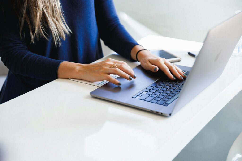 Iemand typt een tekst op een laptop aan een bureau