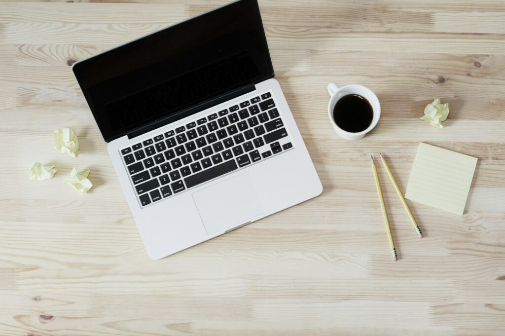 Manuscript met aantekeningen naast een laptop op een houten bureau